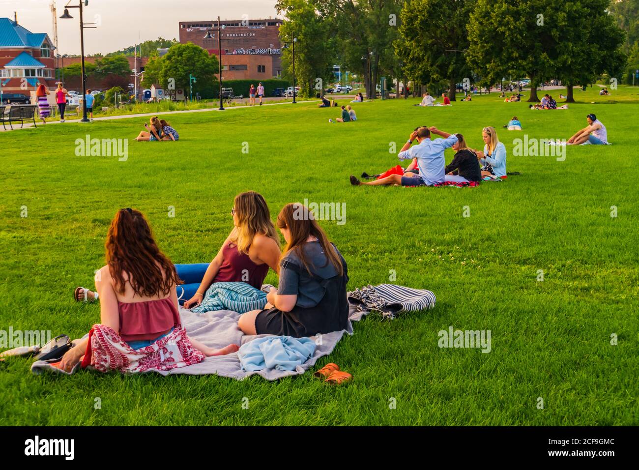 Burlington, Vermont/ USA-23. August 2020: Menschen sitzen auf Rasen am Ufer des Lake Champlain soziale Distanzierung, während sie den Sonnenuntergang beobachten Stockfoto