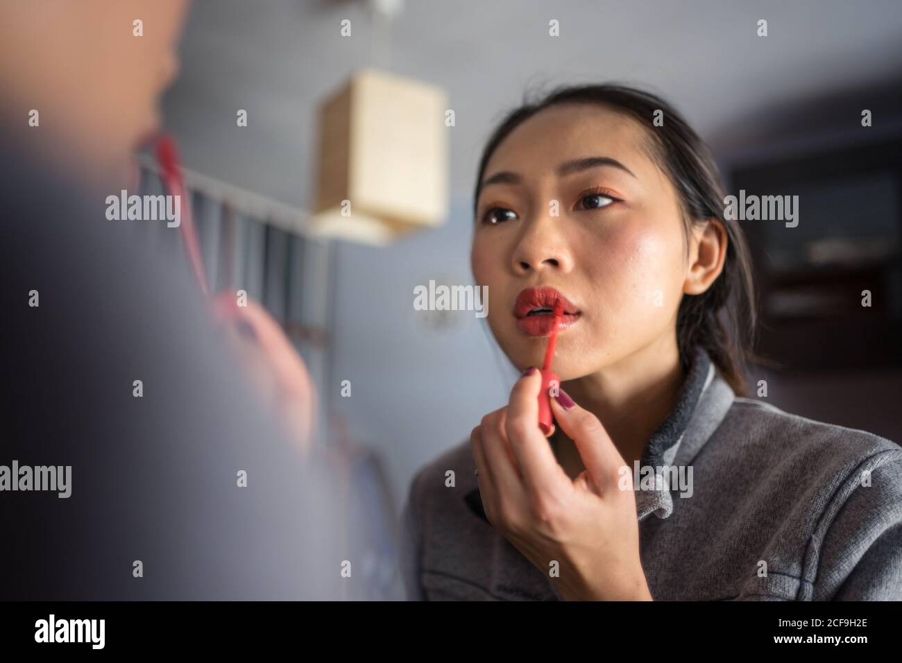 Junge Frau mit Lippenstift vor dem Spiegel Stockfoto