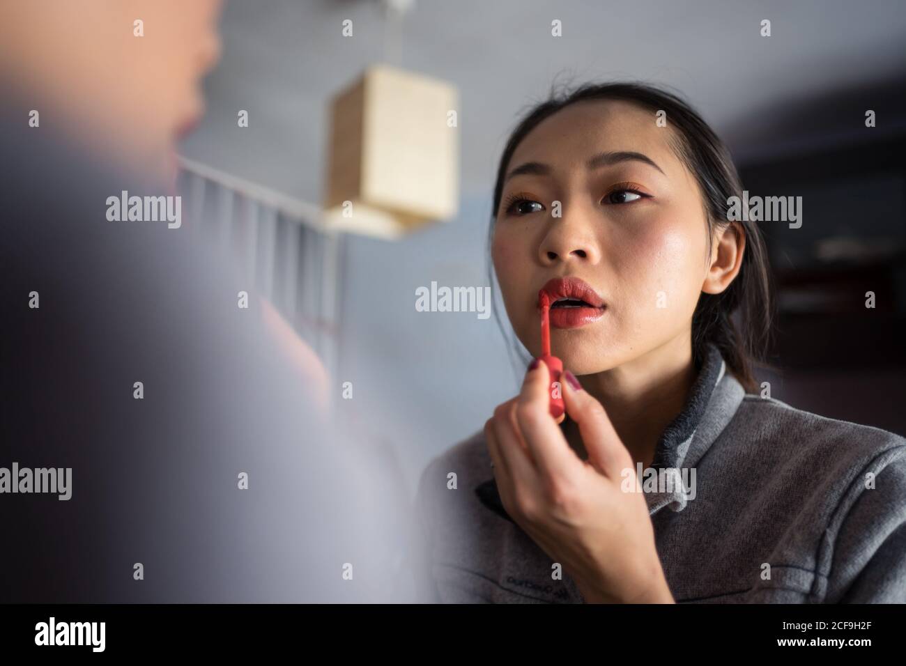 Junge Frau mit Lippenstift vor dem Spiegel Stockfoto