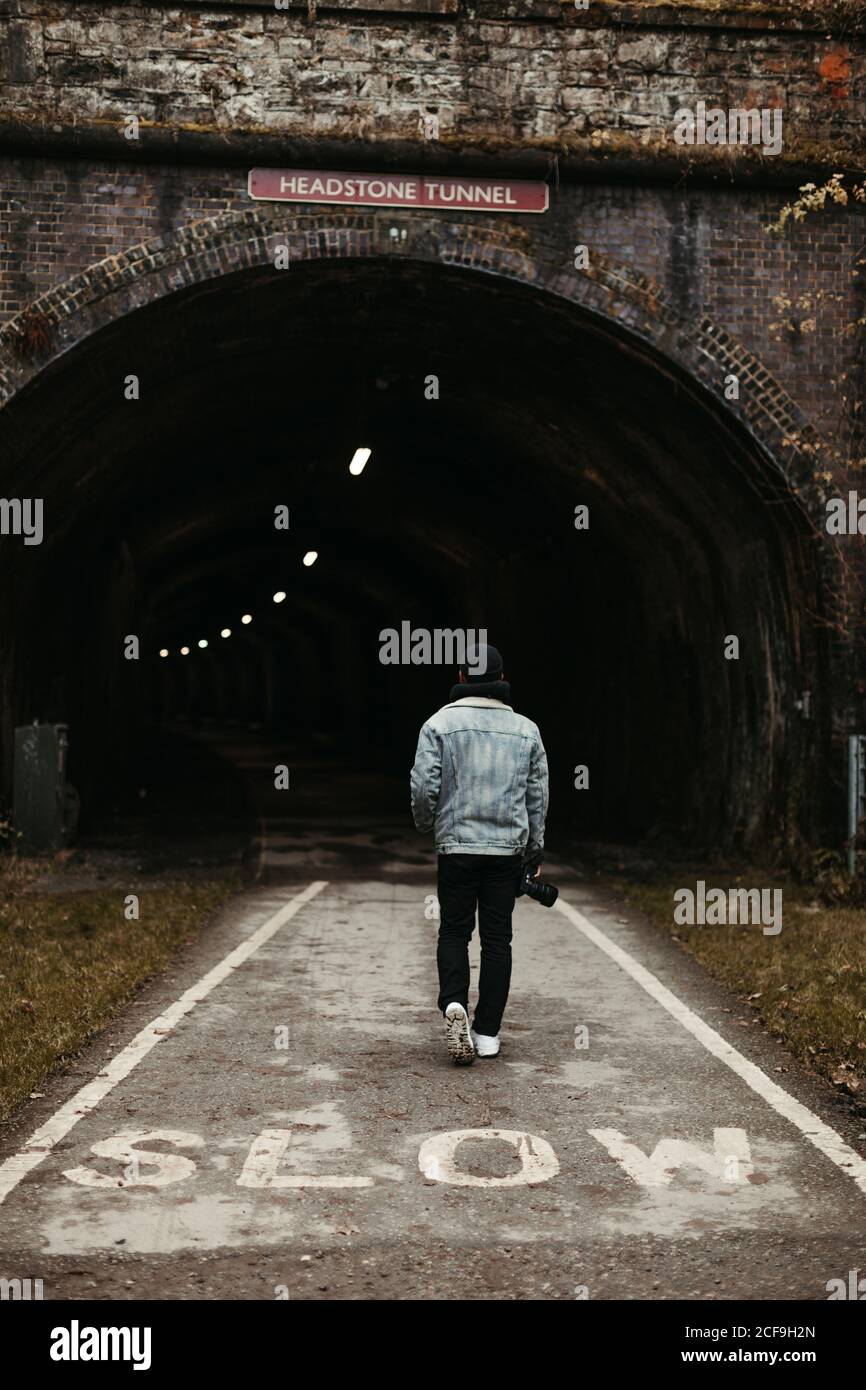 Mann, der auf der Straße vor einem dunklen Tunnel läuft Stockfoto