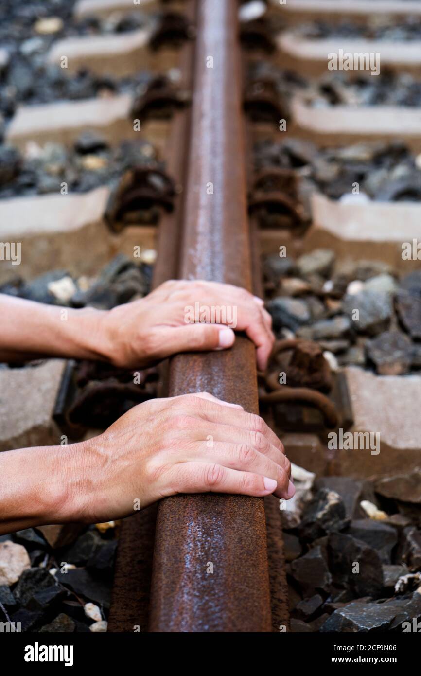 Nahaufnahme der Hände eines kaukasischen Mannes auf dem Eisenbahnschienen Stockfoto