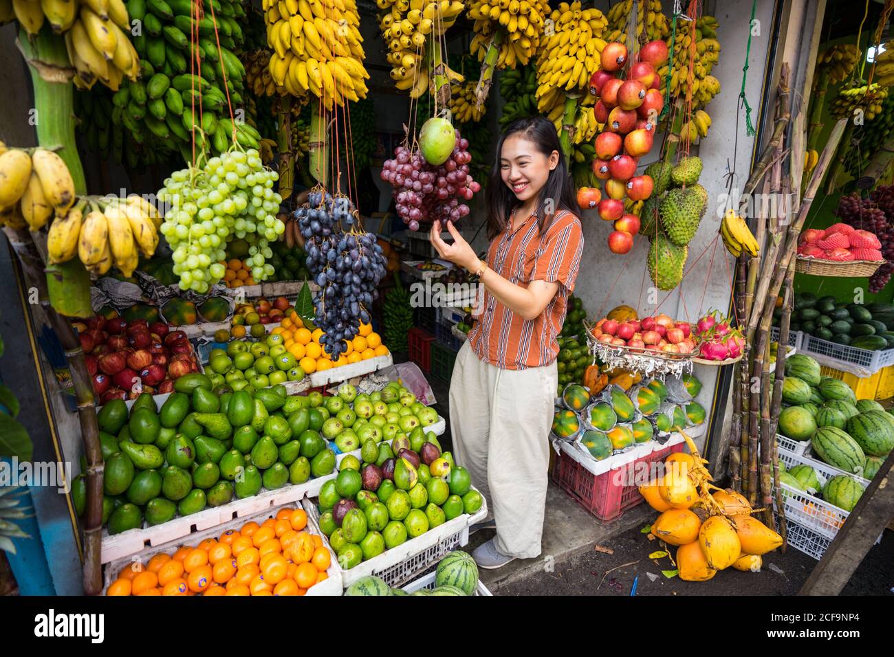 Von oben von Asian erfreut Frau im Urlaub in lässiger Kleidung, die Wahl von frischem Obst auf dem Markt in Sri Lanka Stockfoto