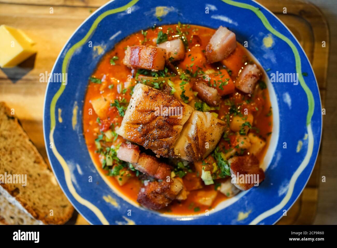 Blick von oben auf eine leckere Platte mit Fischstücken Mit roter Sauce und Grün auf Holztisch Stockfoto