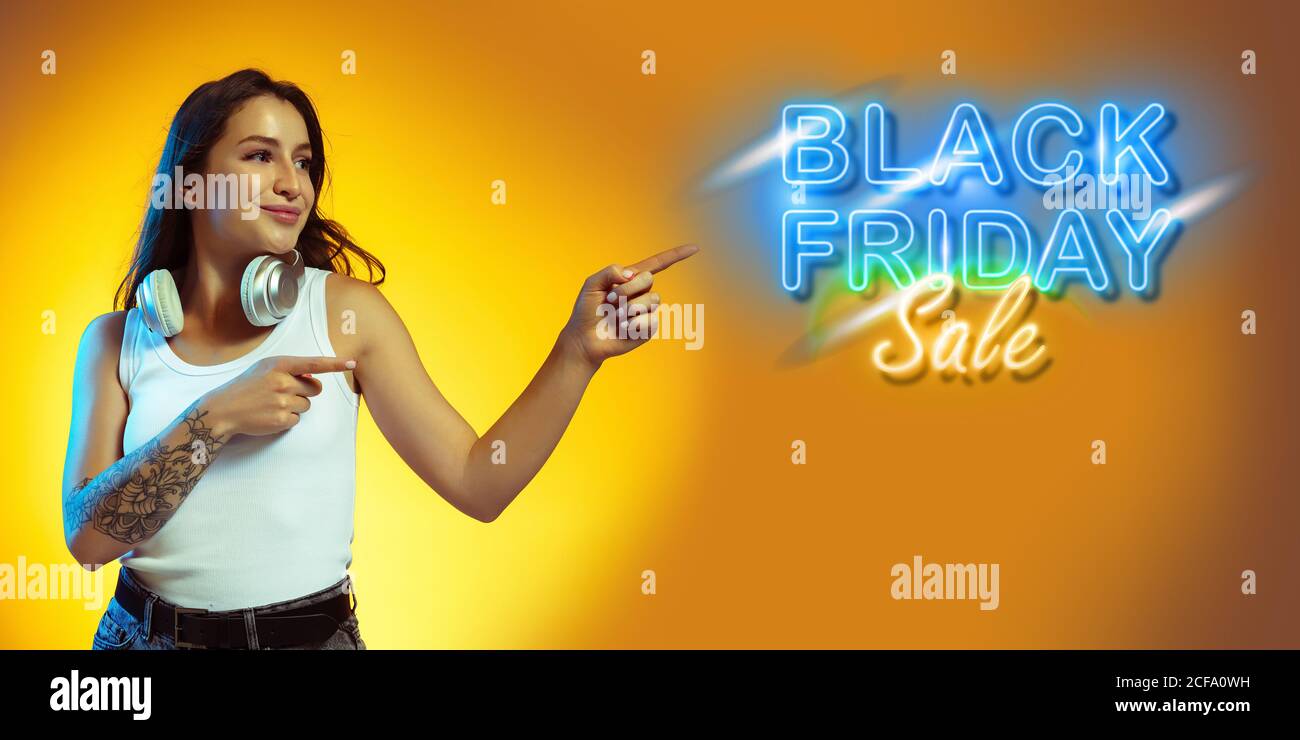 Zeigen. Porträt einer jungen Frau in Neon auf gelbem Studiohintergund. Menschliche Emotionen, Black friday, Cyber monday, Käufe, Verkäufe, Finanzierungskonzept. Copyspace. Nahtlose Post für instagram. Stockfoto