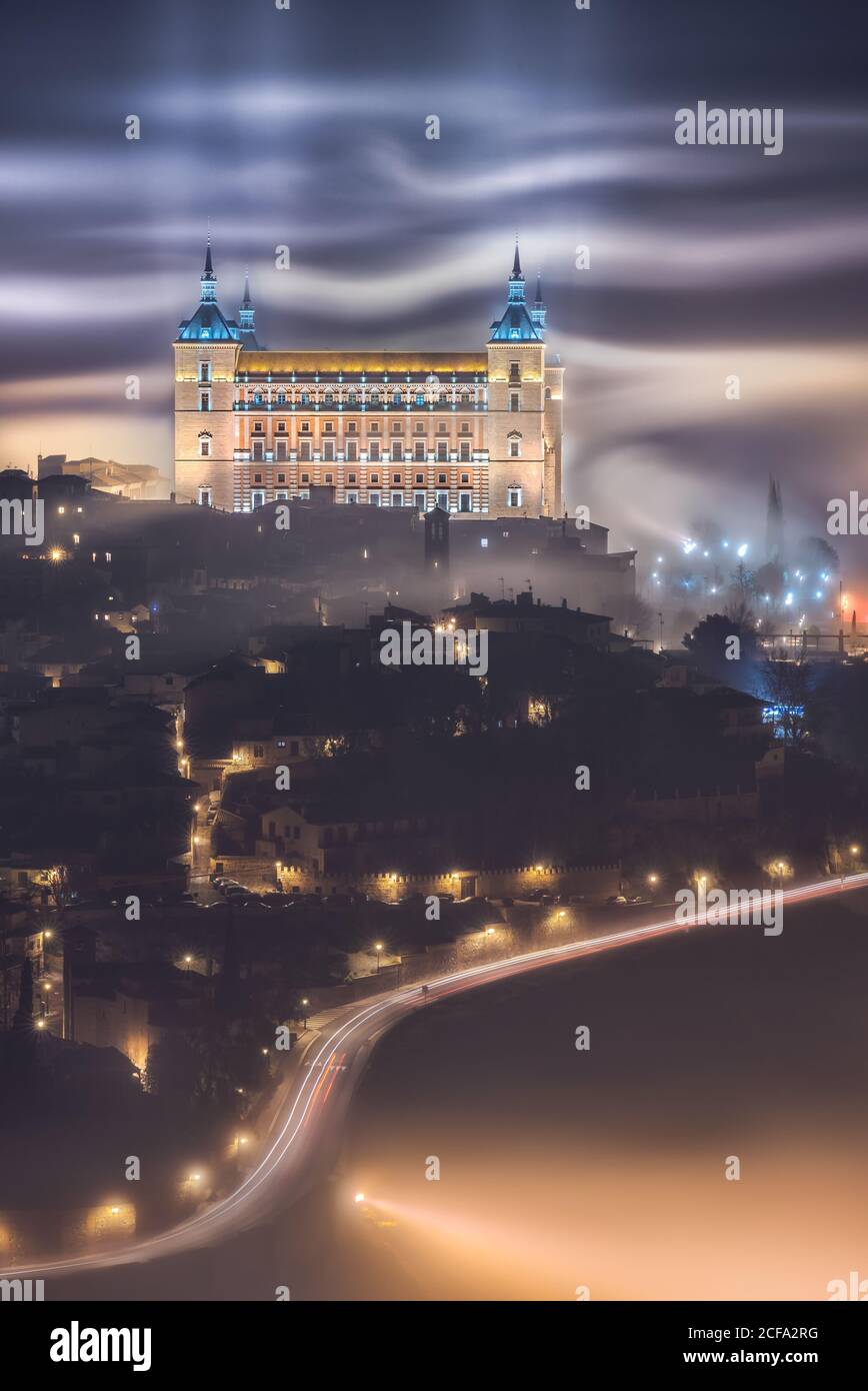 Von oben erstaunliche Landschaft der beleuchteten alten Alcazar de Toledo Burg über der Stadt in nebliger Dämmerung Stockfoto