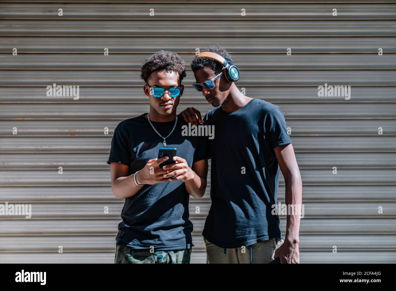 Cool jugendlich afroamerikanischen männlichen Teenagern in Sonnenbrillen  fotografieren Mit Mobiltelefon, während Sie im Sonnenlicht auf der Straße  stehen Stockfotografie - Alamy