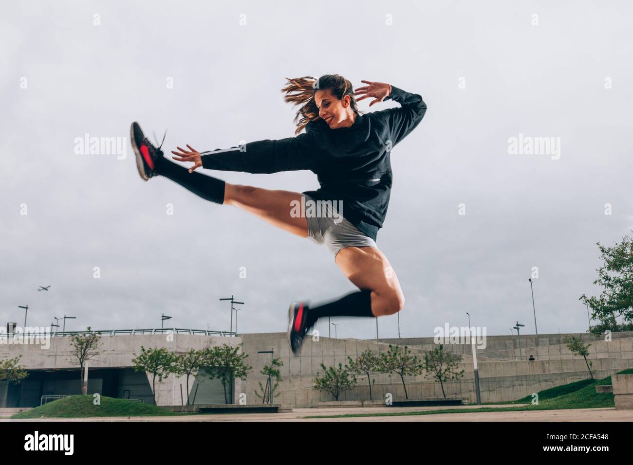 Tänzerin im aktiven tragen lächelnd beim Tanzen im Sprung Im Freien Stockfoto