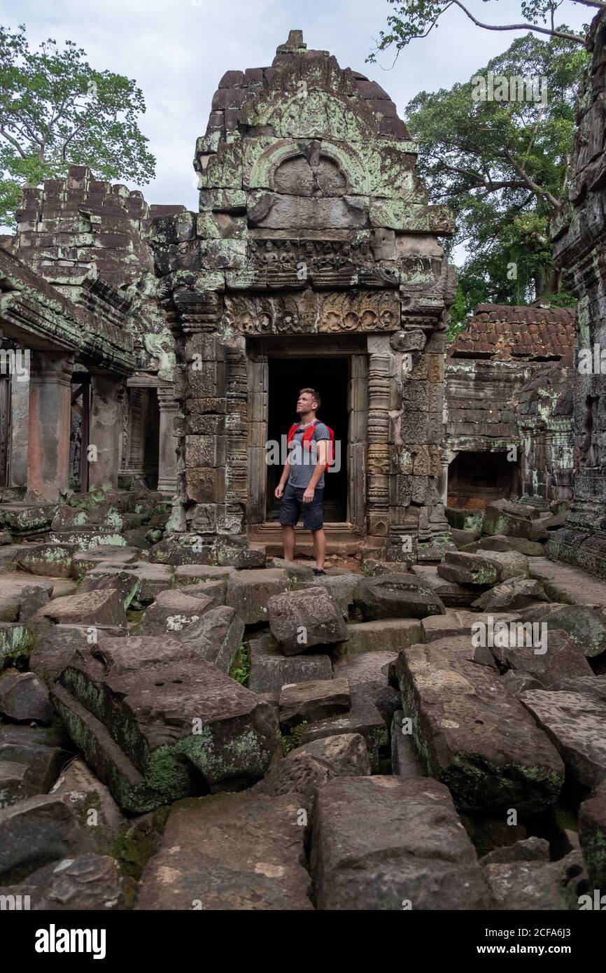 Sorgloser Mann mit Rucksack, der während des Standens an einem historischen Ort nachdenkt Ruinen des religiösen Tempels von Angkor Wat in Kambodscha Stockfoto