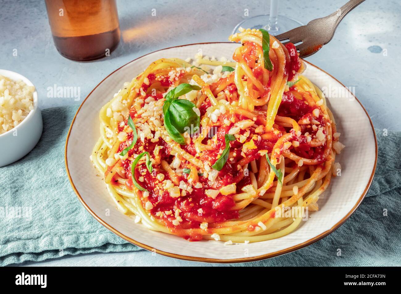 Italienische Pasta, Gabel über Teller gehoben. Spaghetti mit Tomatensauce, Käse und Basilikum Stockfoto