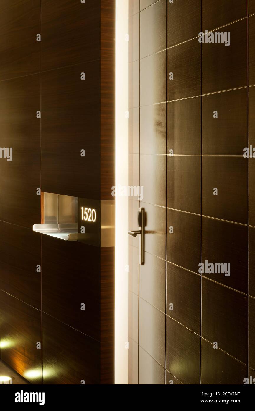 Einfache Zimmertür im beleuchteten Flur im Hotel gestaltet In minimalistischem Stil Stockfoto
