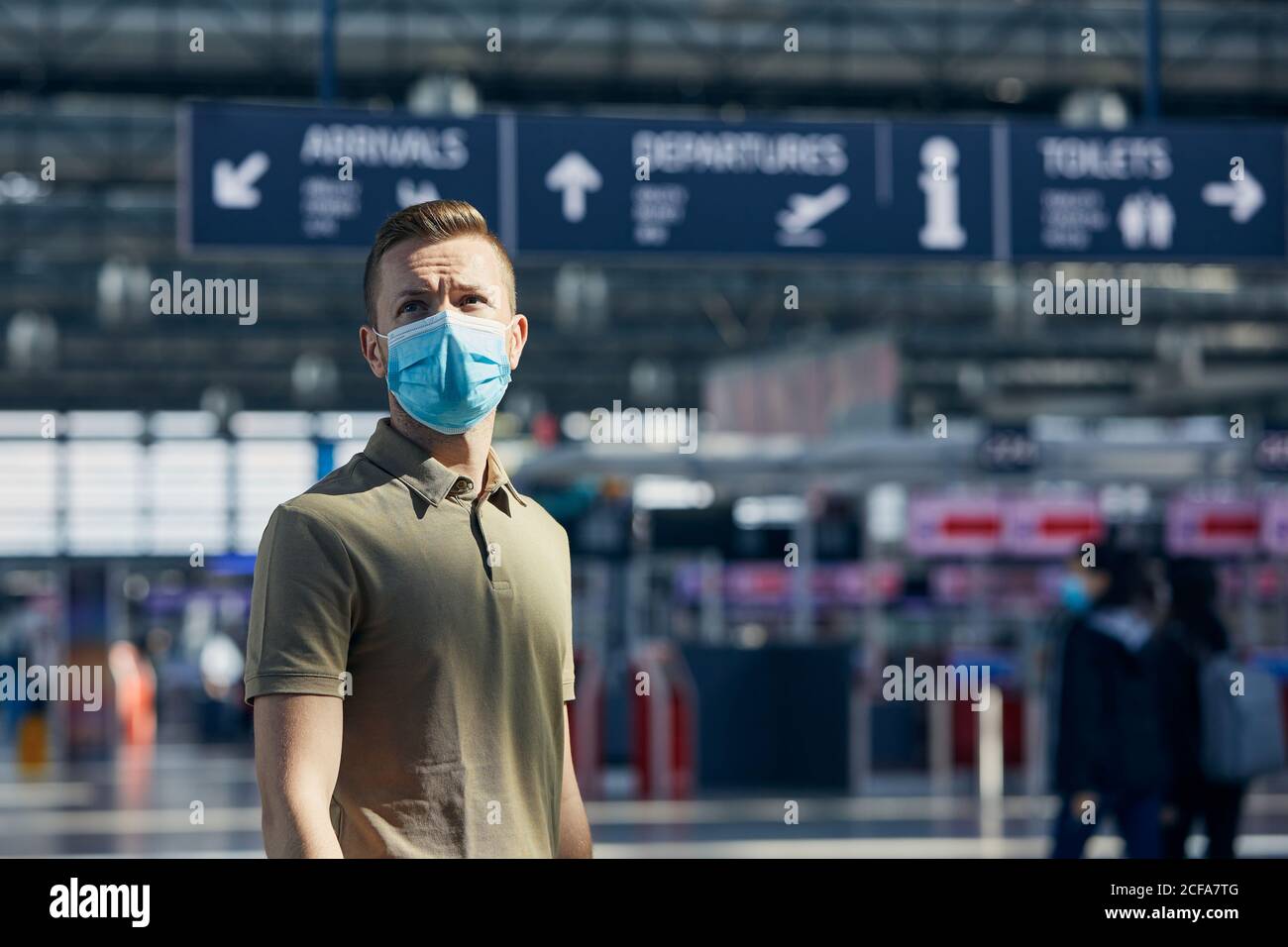 Mann mit Gesichtsmaske am Check-in-Schalter am Flughafen. Themen Reisen in neuer Normalität, Coronavirus und persönlicher Schutz. Stockfoto