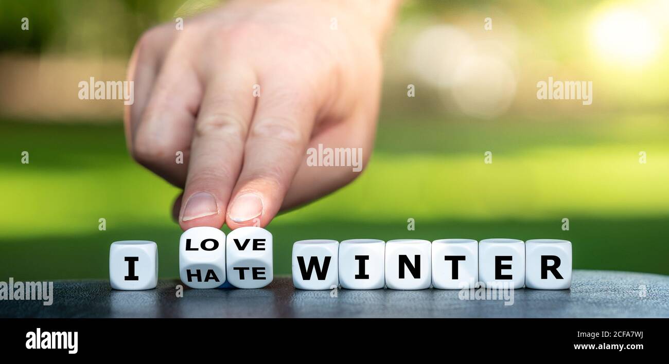 Die Hand dreht Würfel und ändert den Ausdruck "Ich hasse den Winter" in "Ich liebe den Winter". Stockfoto