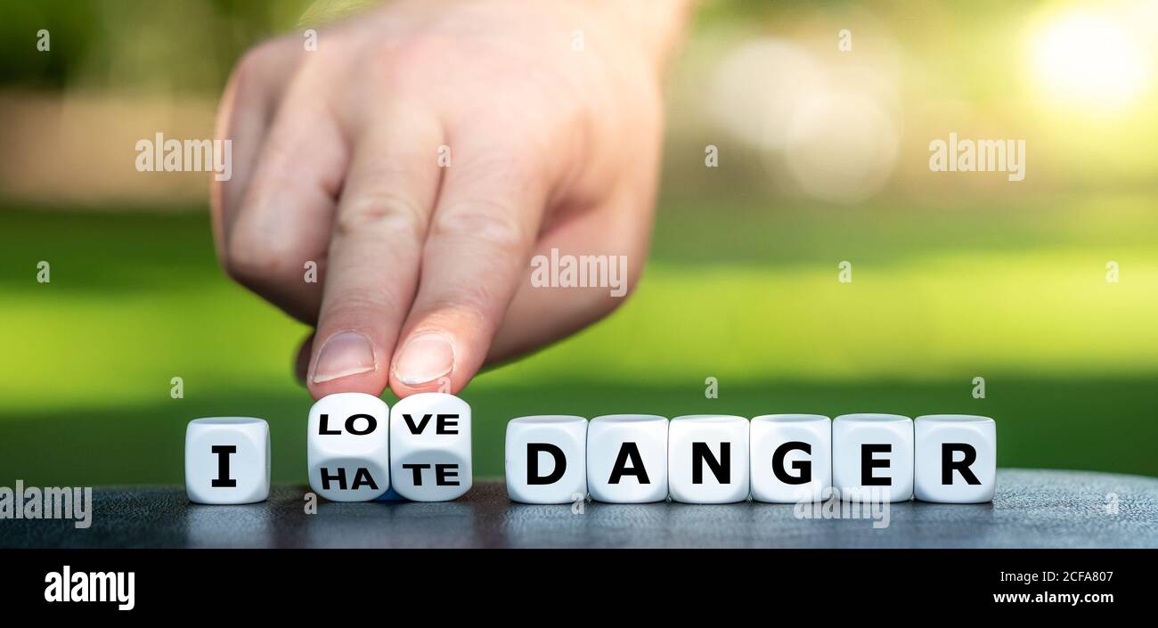 Hand dreht Würfel und ändert den Ausdruck "Ich hasse Gefahr" zu "Ich liebe Gefahr". Stockfoto