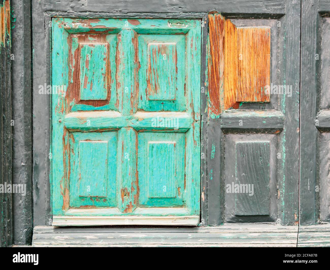 Altes Holzfenster mit teilweise eingefärbten Fensterläden Türkis Stockfoto