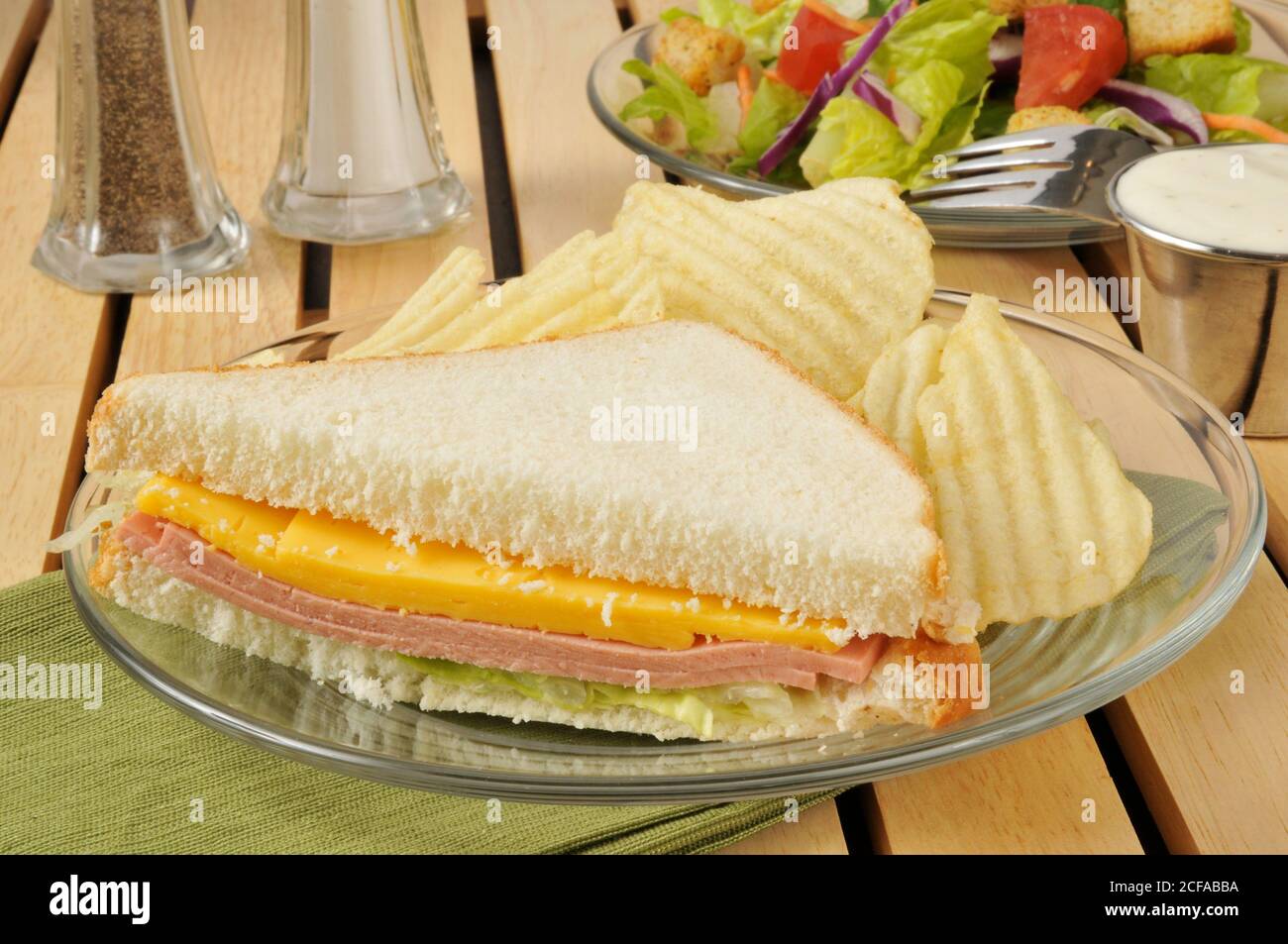 Ein bologna und Käse Sandwich mit amerikanischem Käse, Chips und einem Salat Stockfoto