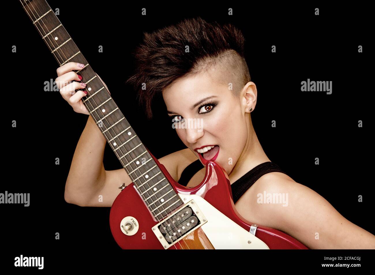 Fokussierte junge Rockerin mit E-Gitarre im Studio Stockfoto