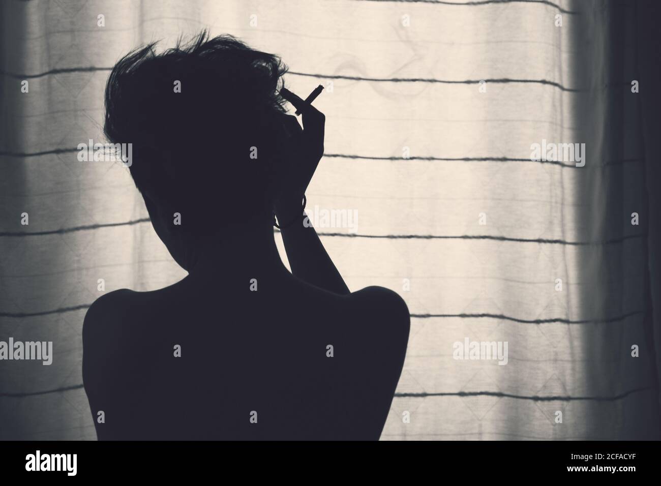 Gesichtslose Silhouette einer ruhigen Frau vor dem Vorhang Stockfoto