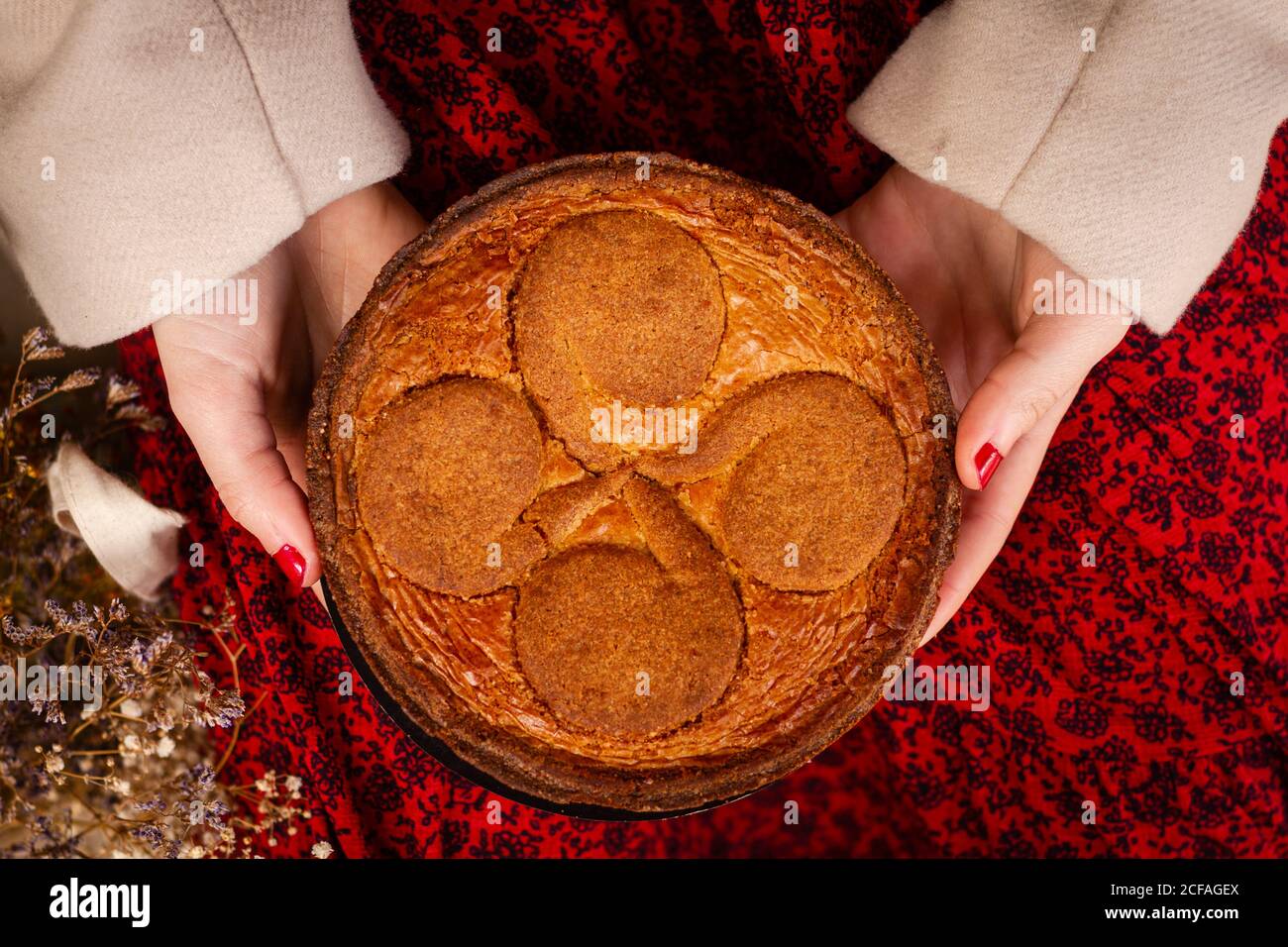 Nicht erkennbare Frau in rotem Kleid sitzt mit leckeren Kuchen auf dem Schoß Stockfoto