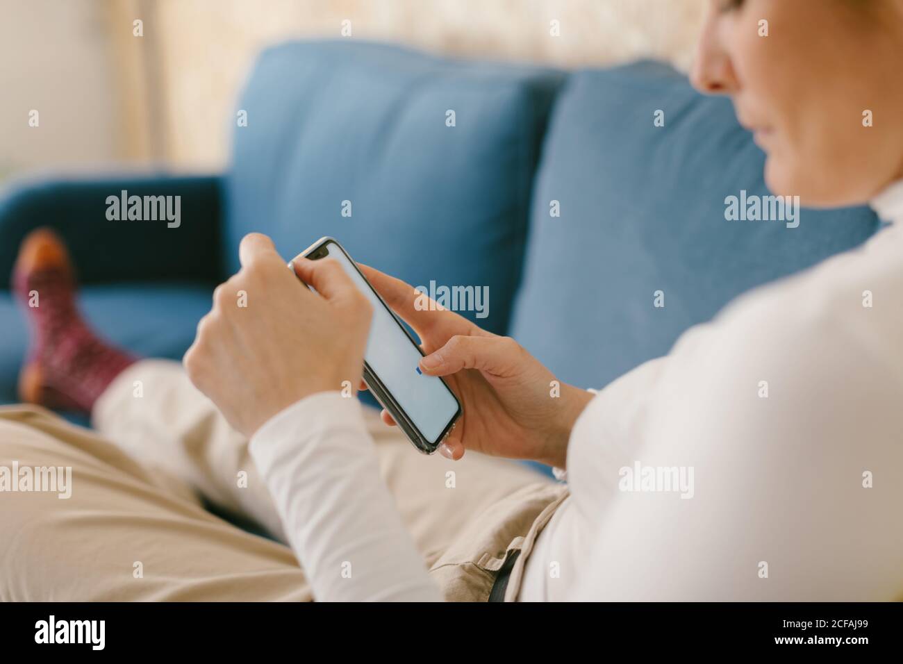 Gesichtslose Frau ohne Schuhe chillen auf gemütlichen Sofa in Büro bei  einer Tasse Kaffee und beim Surfen auf dem Handy Stockfotografie - Alamy