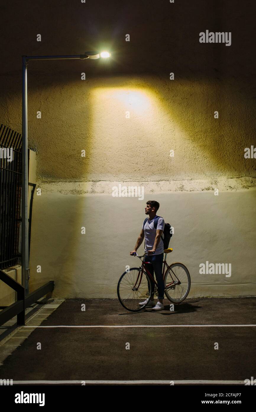 Vorderansicht eines Mannes, der ein Fahrrad von einem nimmt Parken in der Nacht nach Hause zu gehen Stockfoto