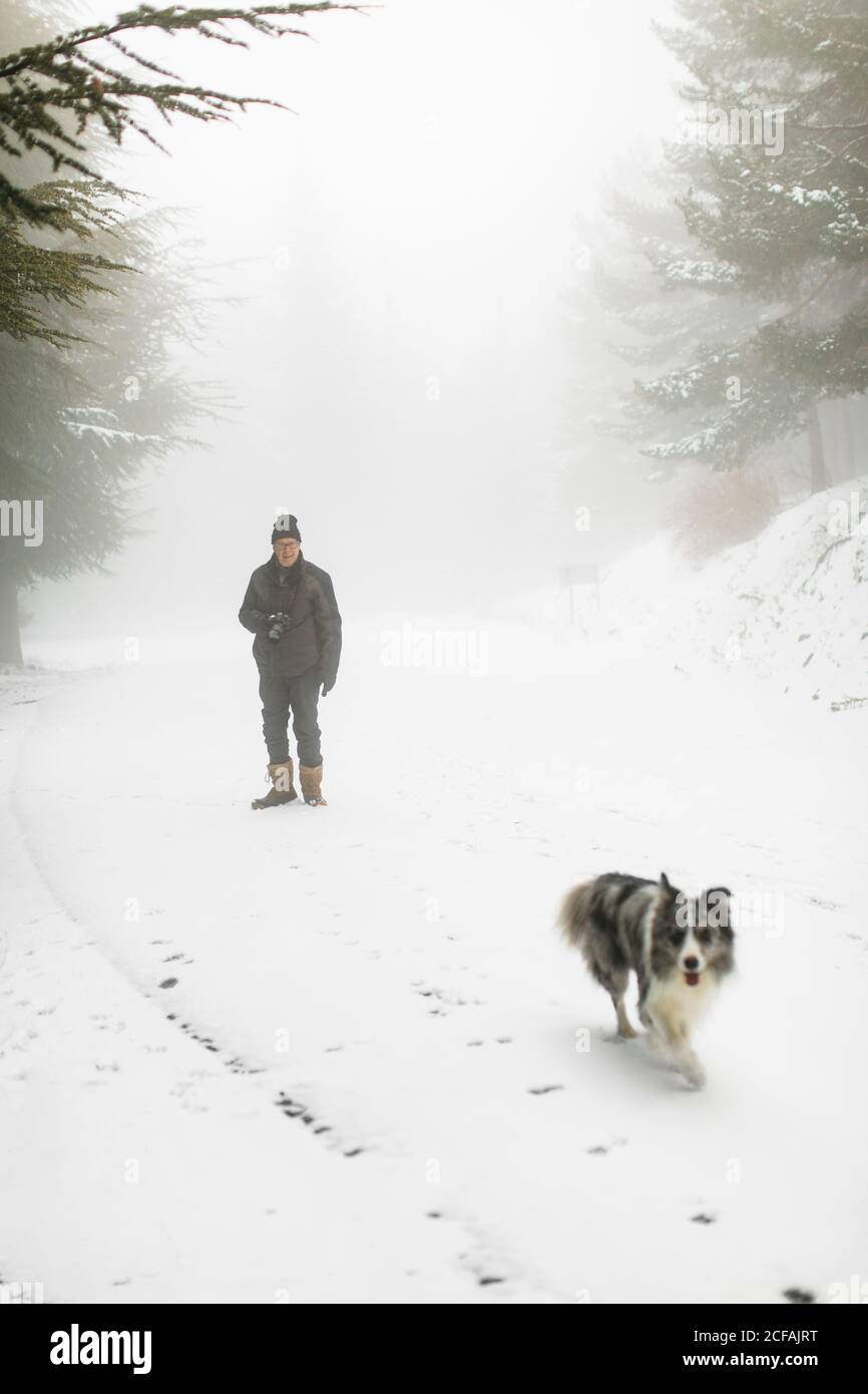 Älterer Kaukasianer und sein Hund wandern im Schnee Stockfoto