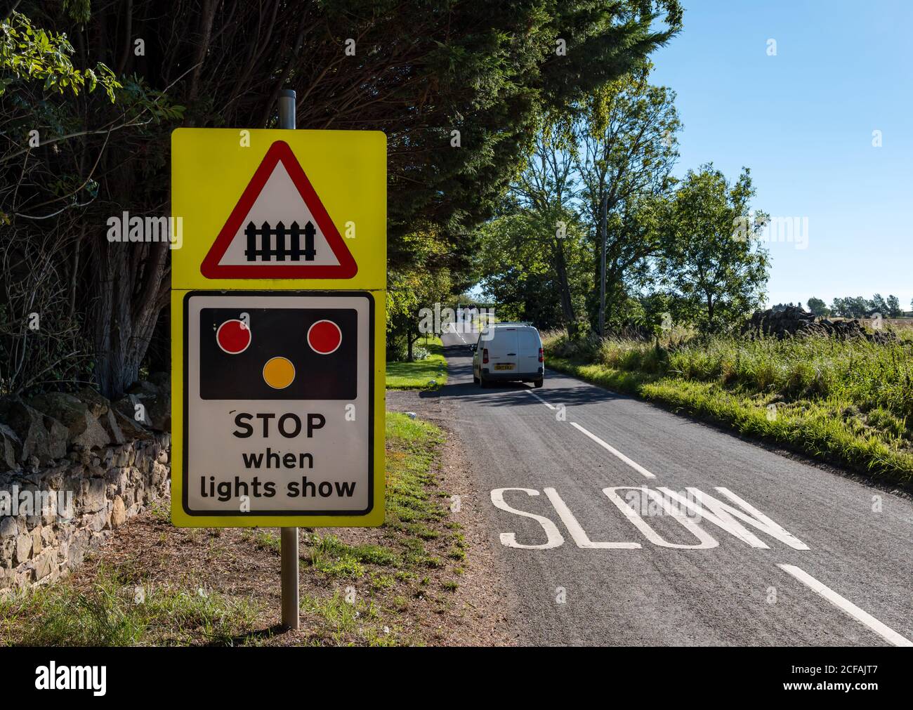 Straßenwarnung langsam und Stop-Zeichen auf East Coast Hauptlinie Bahnlinie Bahnübergang, Markle, East Lothian, Schottland, Großbritannien Stockfoto