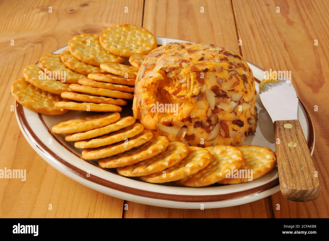 Cheddar Cheeseball mit geschnittenen Mandeln und Crackern Stockfoto