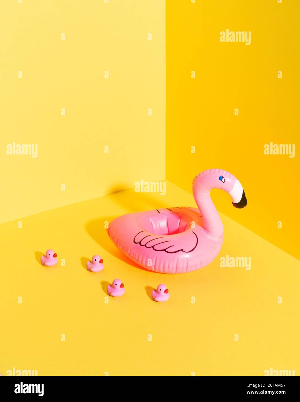 Bunte Komposition mit aufblasbarer Flamingo-Boje und Miniatur-Entenspielzeug Vor gelbem Hintergrund platziert Stockfoto