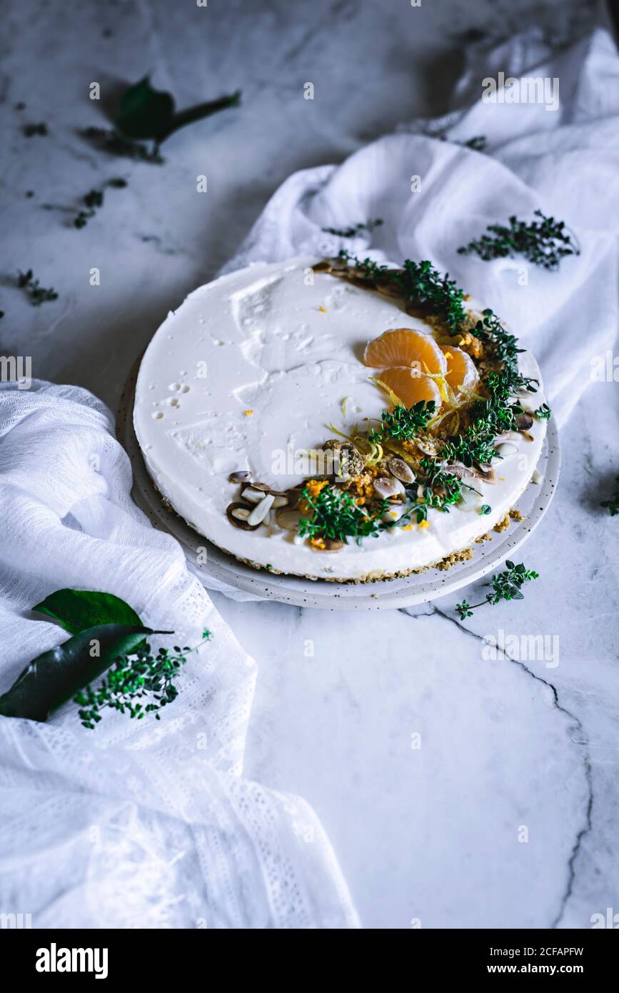 Von oben schmackhaft appetitlich dekoriert mit Mandarinengrün und Nüssen Mandarine Kuchen und ganze Zitrusfrüchte Messer Schüssel mit Löffel auf Tabelle Stockfoto