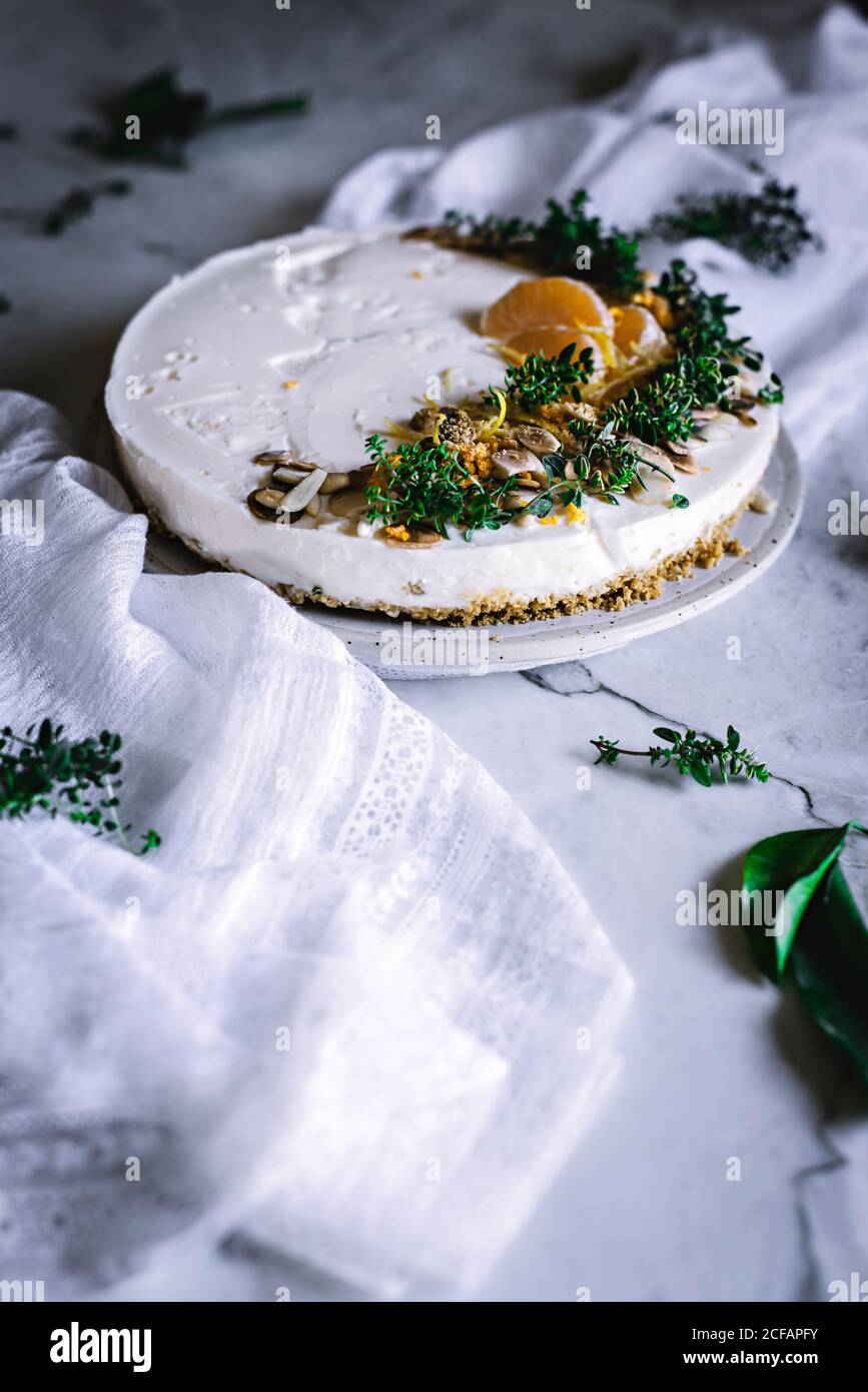 Von oben schmackhaft appetitlich dekoriert mit Mandarinengrün und Nüssen Mandarine Kuchen und ganze Zitrusfrüchte Messer Schüssel mit Löffel auf Tabelle Stockfoto