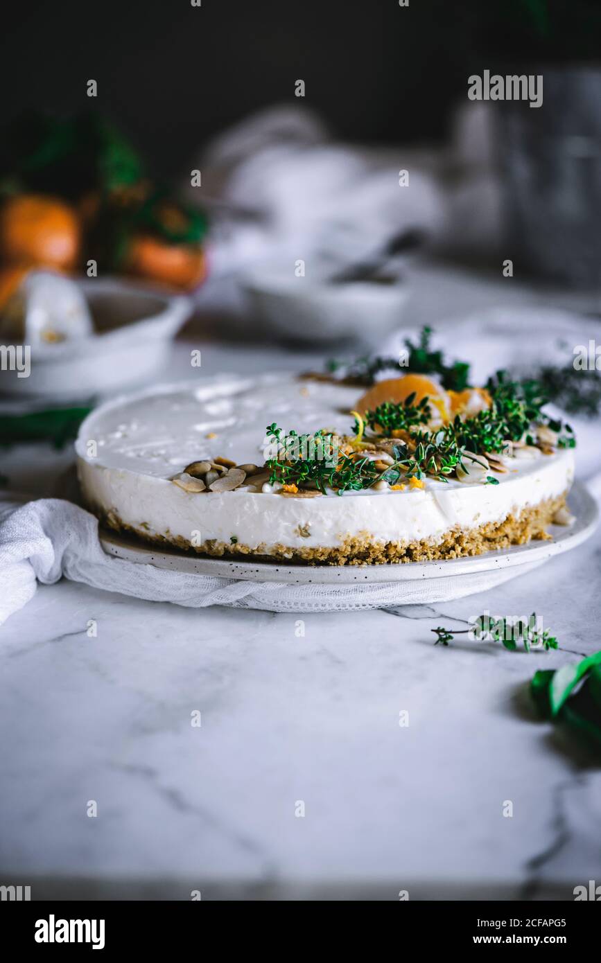 Von oben schmackhaft appetitlich dekoriert mit Mandarinengrün und Nüssen Mandarine Kuchen und ganze Zitrusfrüchte Messer Schüssel mit Löffel auf Tabelle Stockfoto