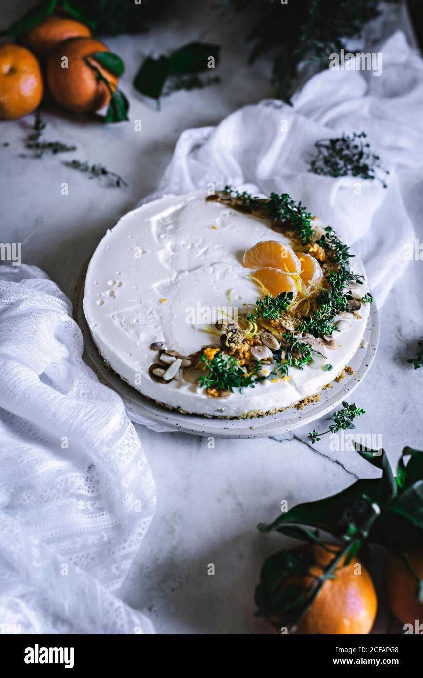 Von oben schmackhaft appetitlich dekoriert mit Mandarinengrün und Nüssen Mandarine Kuchen und ganze Zitrusfrüchte Messer Schüssel mit Löffel auf Tabelle Stockfoto