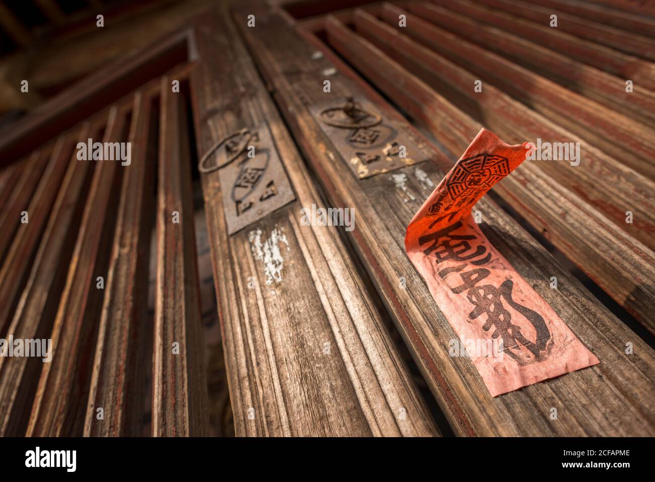 Unten von der alten hölzernen Tür mit den Metallklopfern und Roter Aufkleber mit Hieroglyphen in Daimei Village Stockfoto