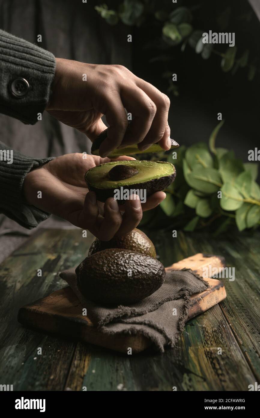 Anonyme Person Hände schneiden Avocados in der Hälfte Guacamole vorzubereiten Stockfoto