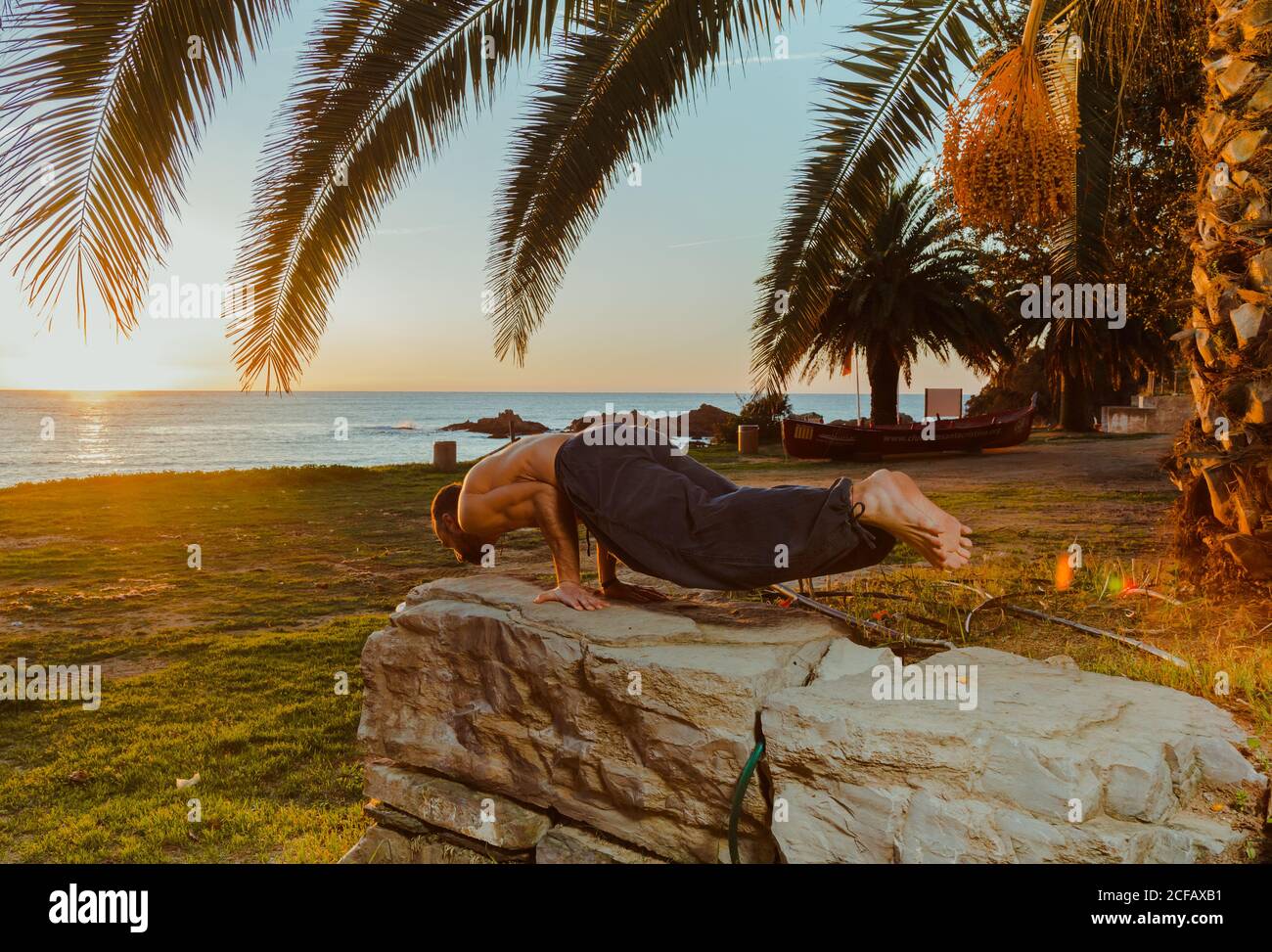 Seitenansicht des fürsorglichen Großvaters, der aktiven Enkelin beim Fahrradfahren mit Korb auf der Straße auf dem Land mit grünen Bäumen am Sommertag hilft Stockfoto