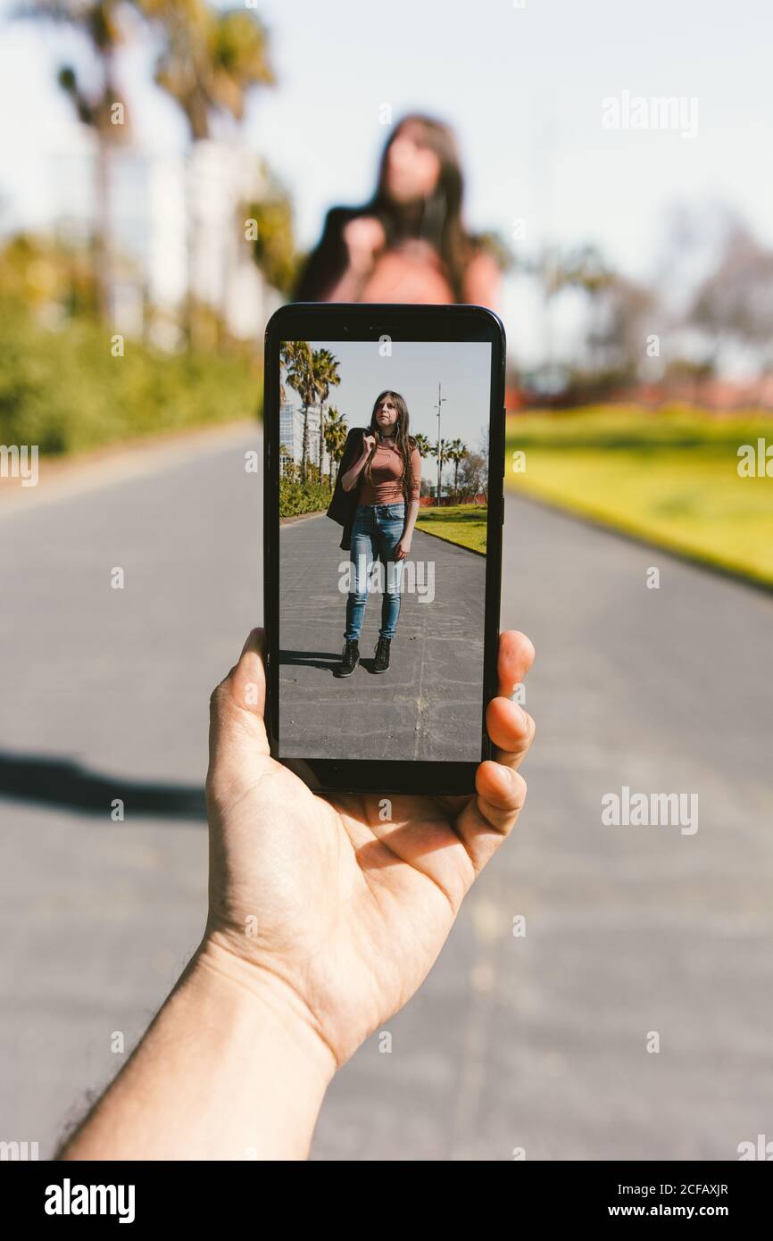 Handaufnahme einer stilvollen modernen Frau mit Smartphone an sonnigen Tagen Stockfoto