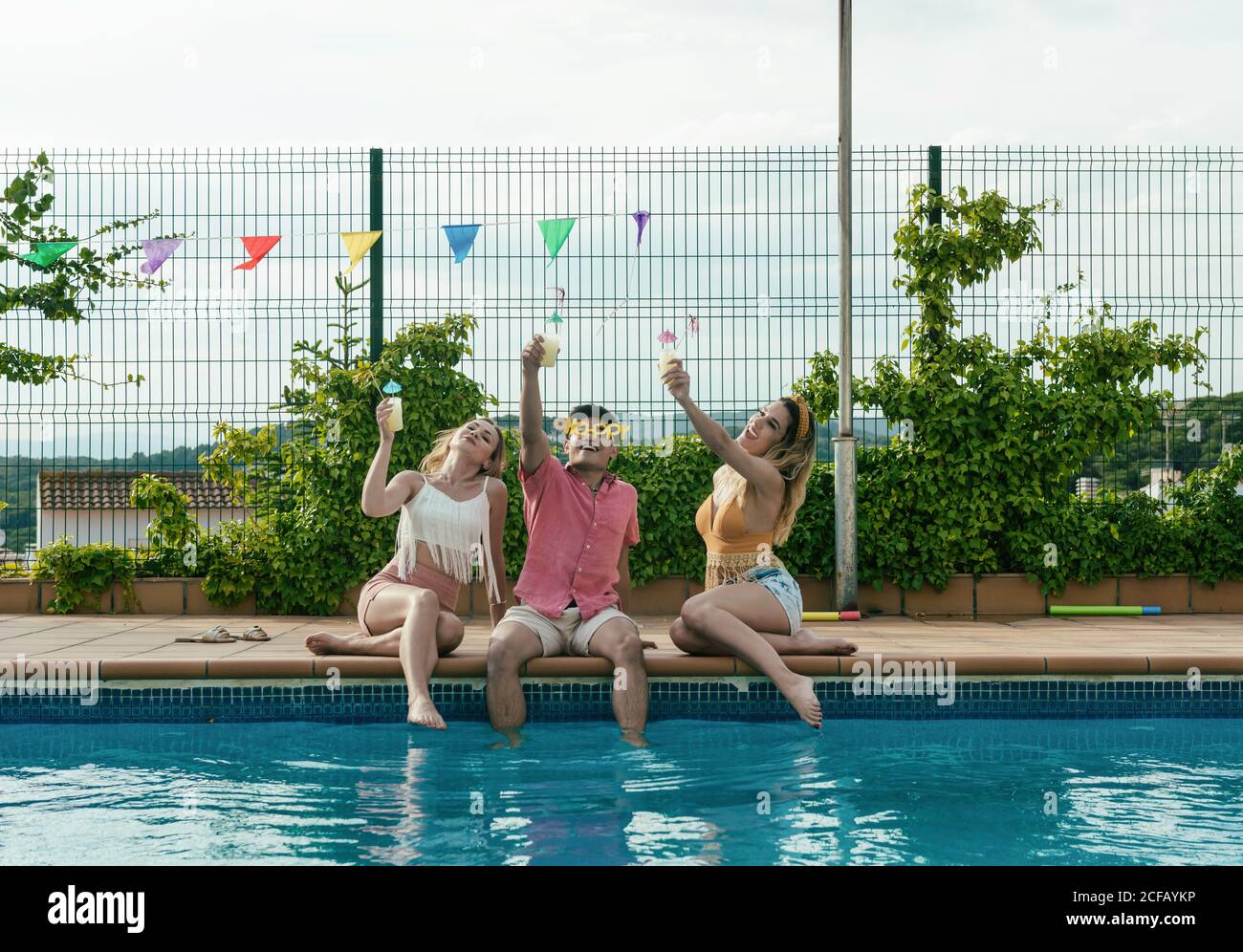 Eine Gruppe von Freunden, die eine Poolparty machen, während sie tanzen, lachen und Cocktails trinken Stockfoto