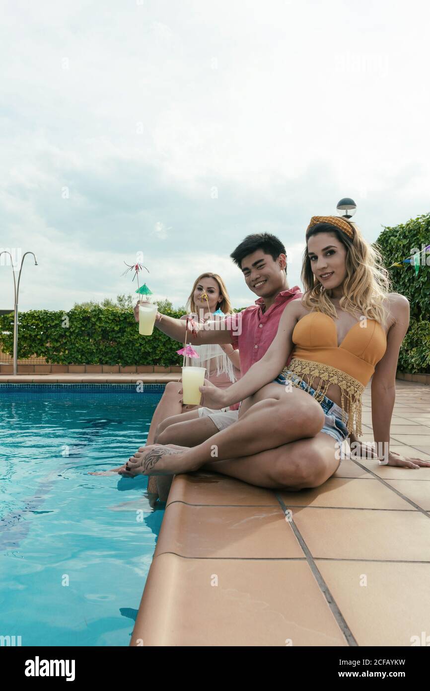 Eine Gruppe von Freunden, die eine Poolparty machen, während sie tanzen, lachen und Cocktails trinken Stockfoto