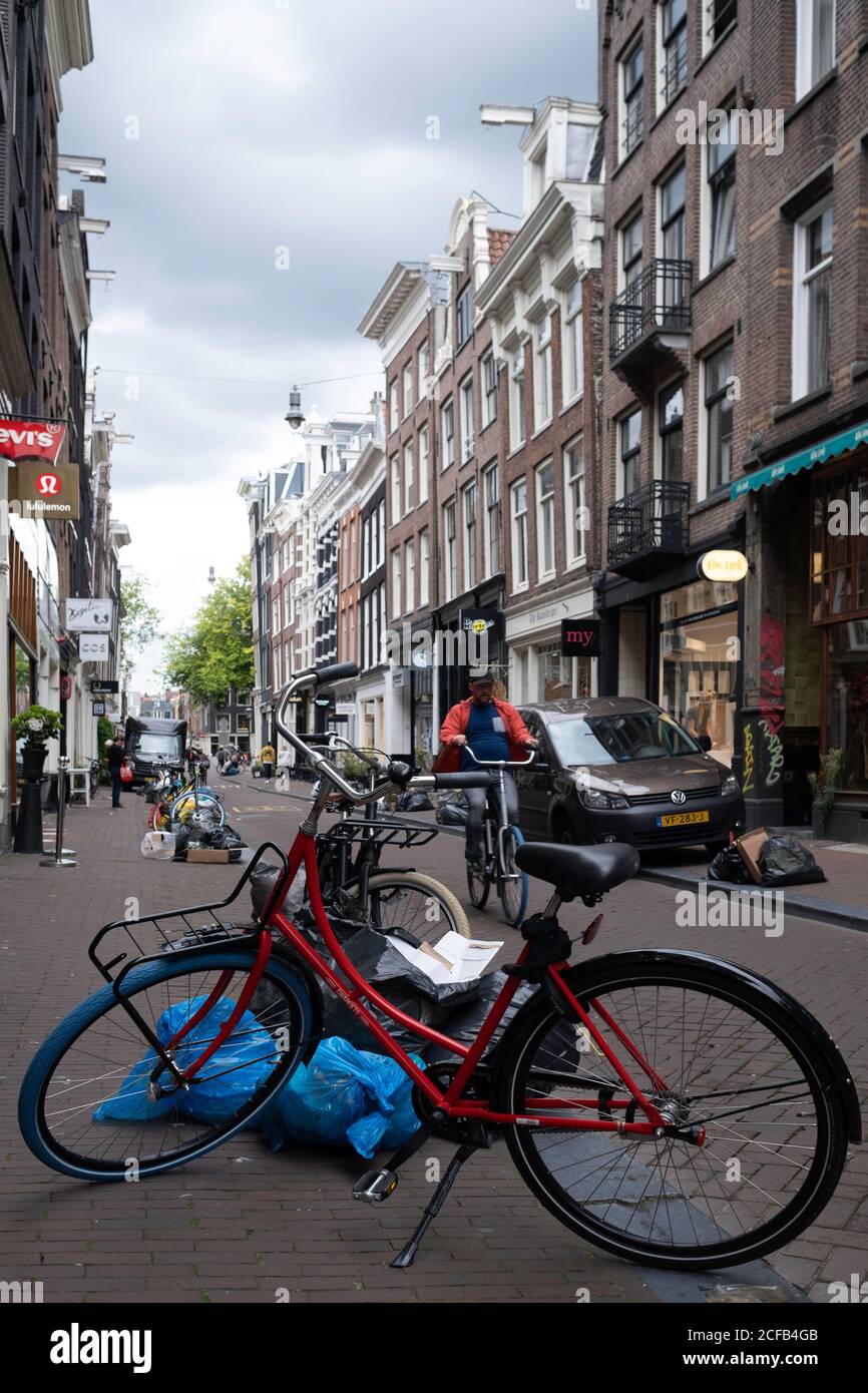 Müllsäcke liegen auf einer Straße mit Fahrrad vor der Tür in der Negen Straatjes (Englisch: Neun kleine Straßen), einem Viertel von Amsterdam Stockfoto