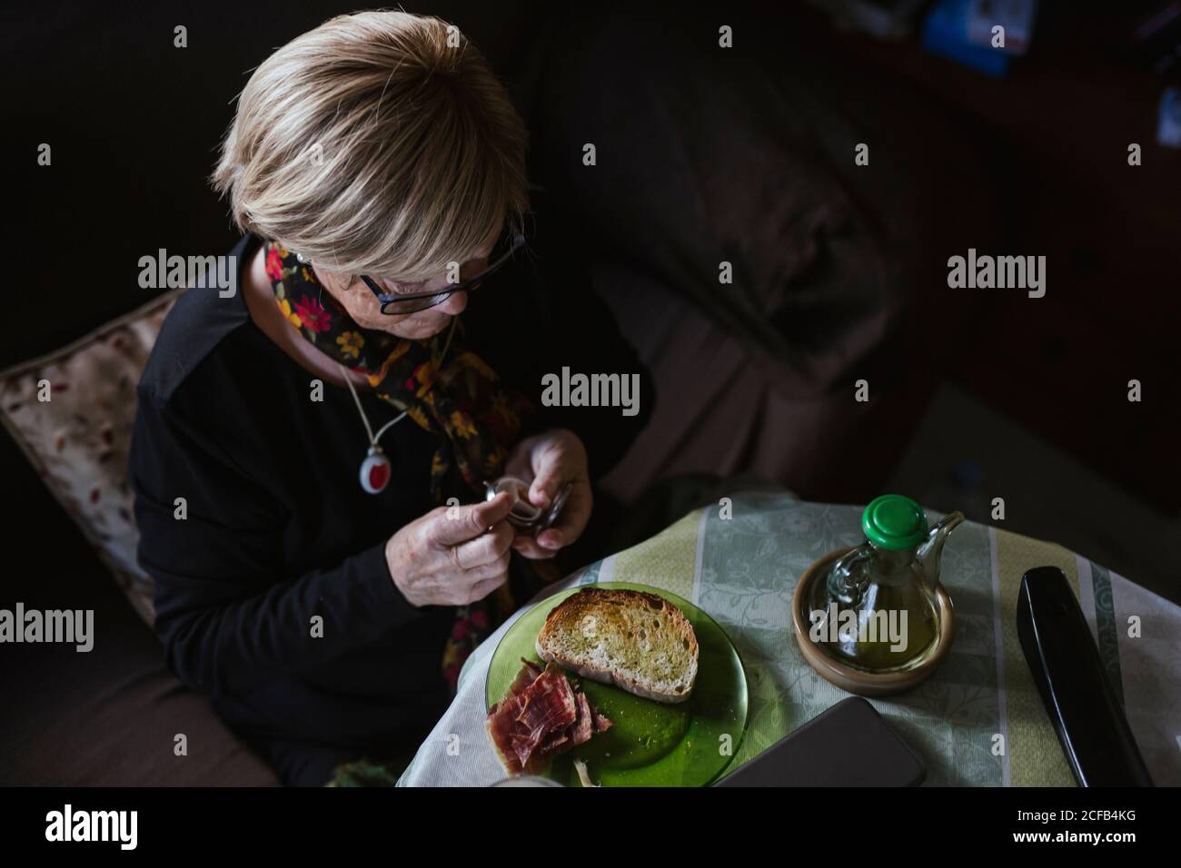 Ältere attraktive Frau, die vor dem Frühstück Medikamente aus der Pillenbox einnahm Stockfoto