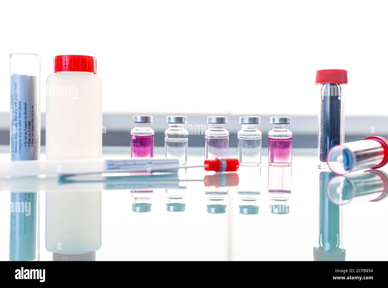 Sterile Röhrchen und medizinische Proben auf Glastisch Stockfoto