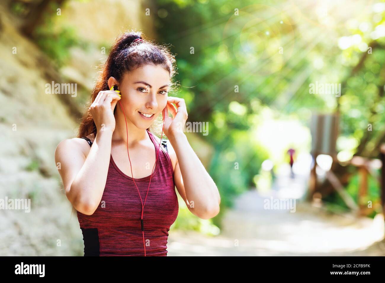 Junge Frau in Sportbekleidung hört Musik auf Kopfhörern, während sie auf der Straße trainiert. Konzept zum Thema gesunder Lebensstil Stockfoto