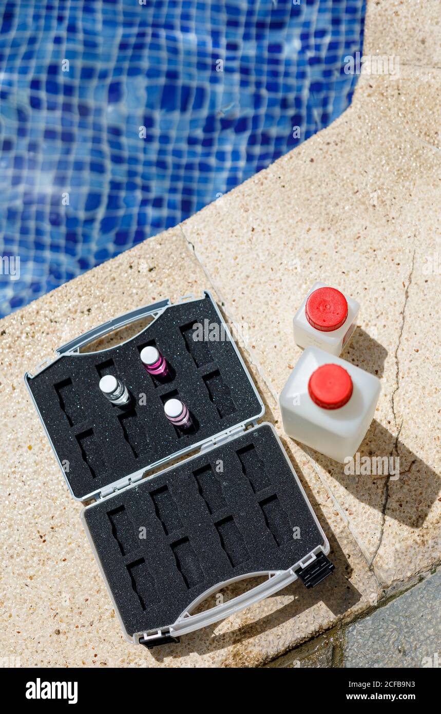 Von oben Flaschen mit Wasserproben und Aktentasche mit Chemikalien In der Nähe des Schwimmbades während der Sicherheitsinspektion im Resort platziert Stockfoto