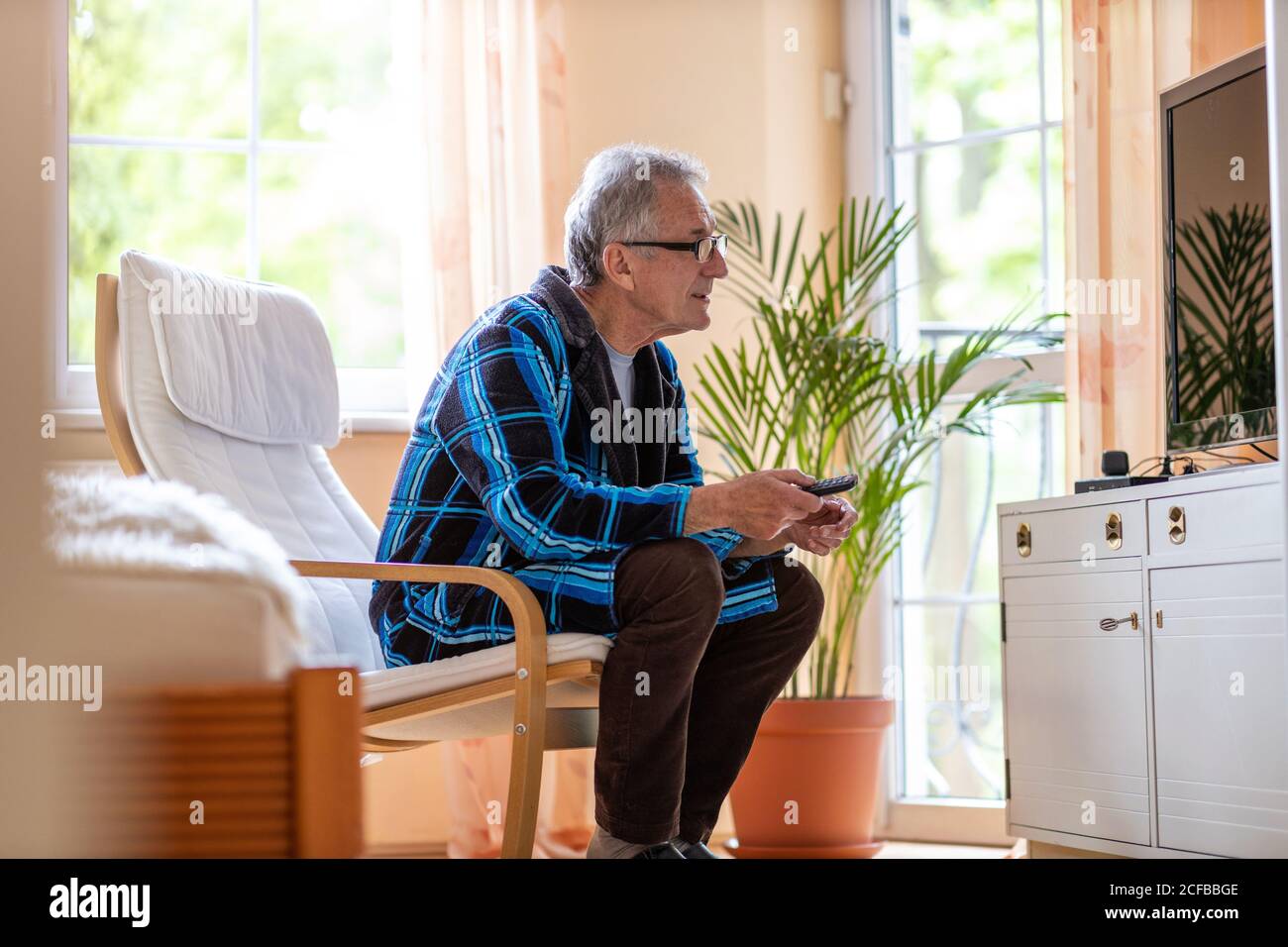 Älterer Mann mit TV-Fernbedienung Stockfoto