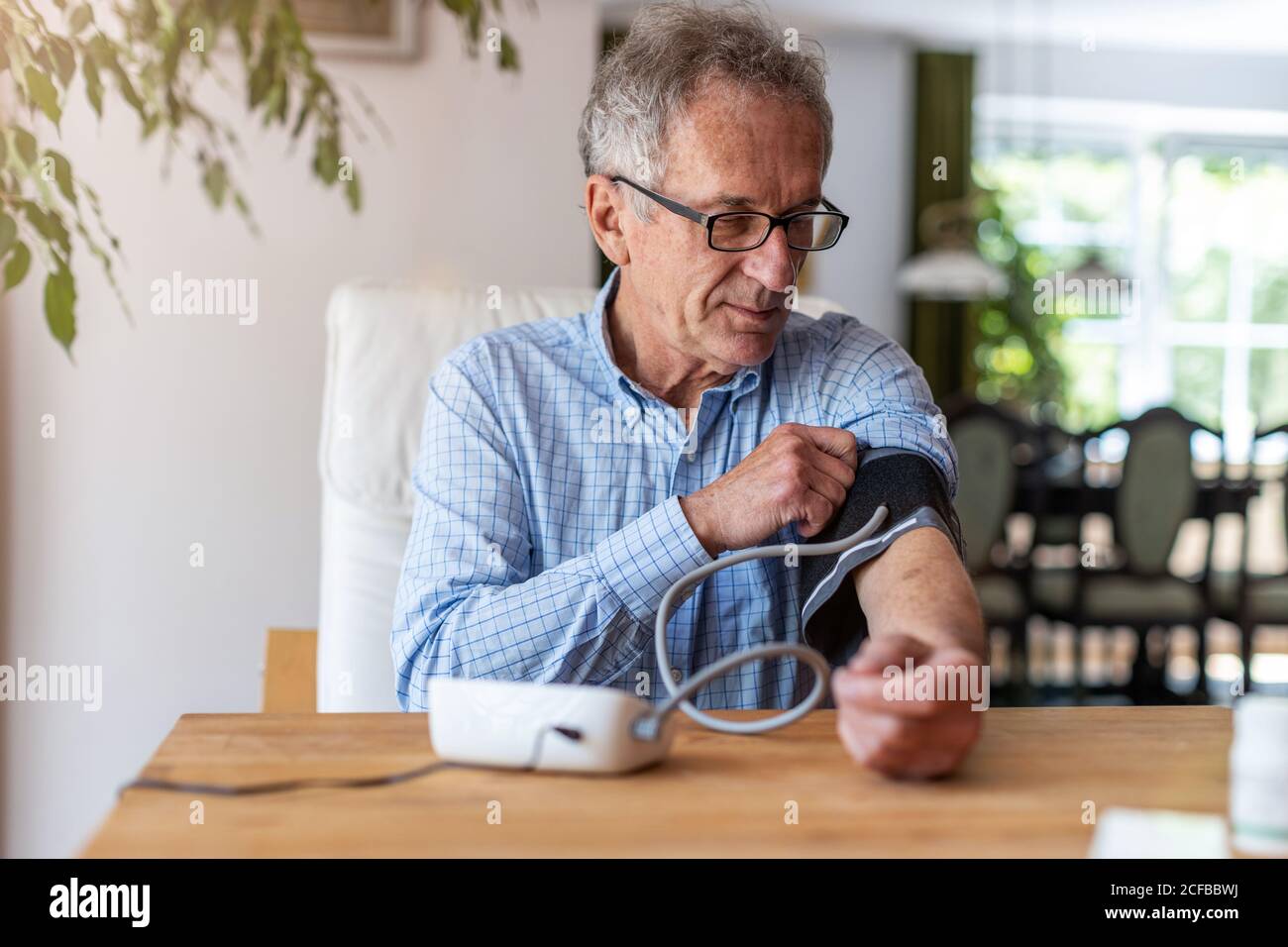 Leitender Mann, der ein medizinisches Gerät zur Blutdruckmessung verwendet Stockfoto