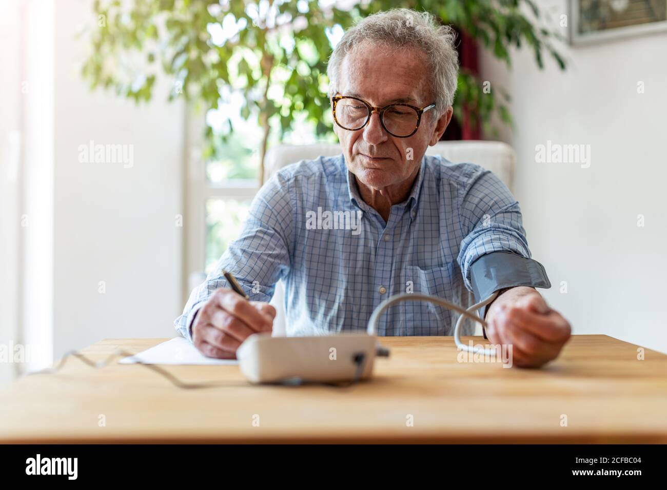 Leitender Mann, der ein medizinisches Gerät zur Blutdruckmessung verwendet Stockfoto