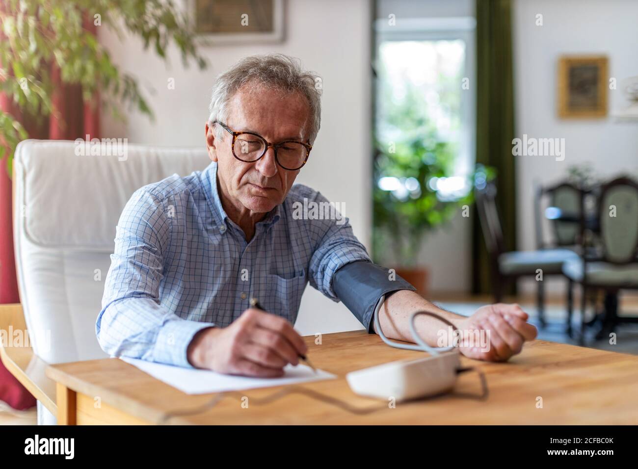 Leitender Mann, der ein medizinisches Gerät zur Blutdruckmessung verwendet Stockfoto