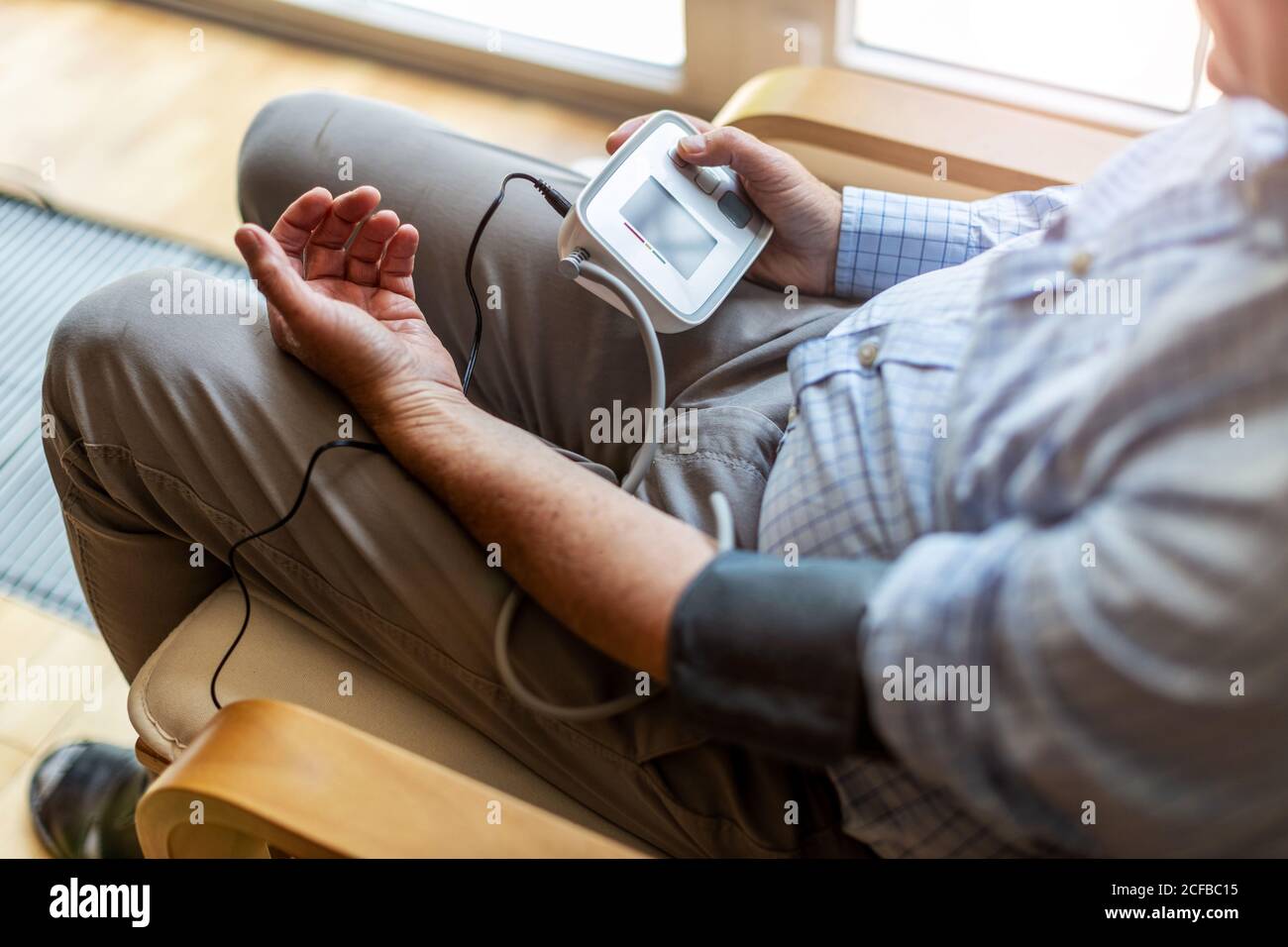 Leitender Mann, der ein medizinisches Gerät zur Blutdruckmessung verwendet Stockfoto