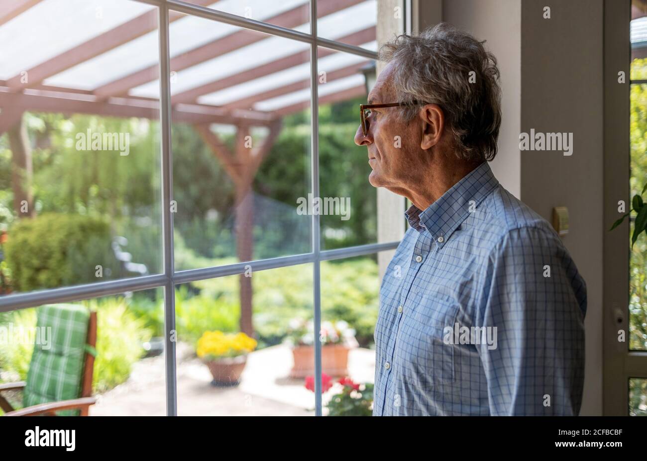 Ältere Menschen, die sich von Fenster zu Hause Stockfoto