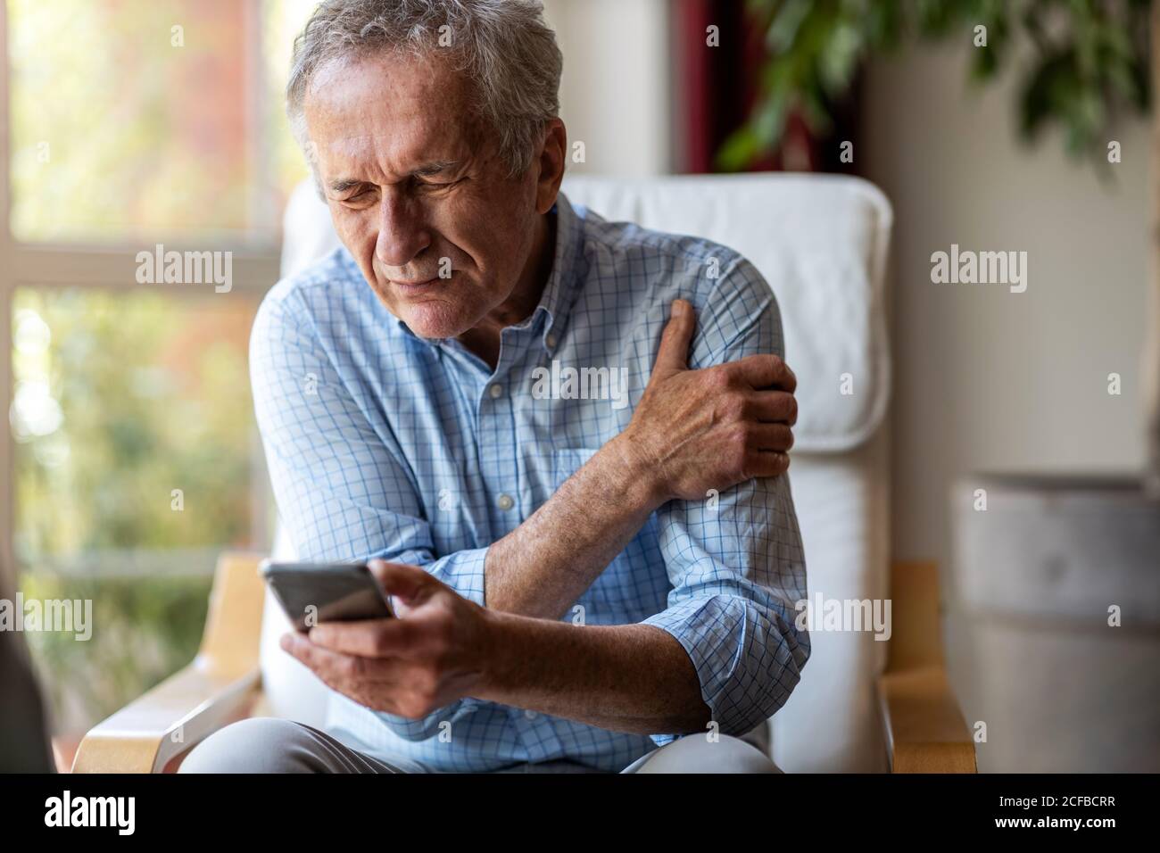 Älterer Mann mit Arthritis, der sich die Hände reibt Stockfoto